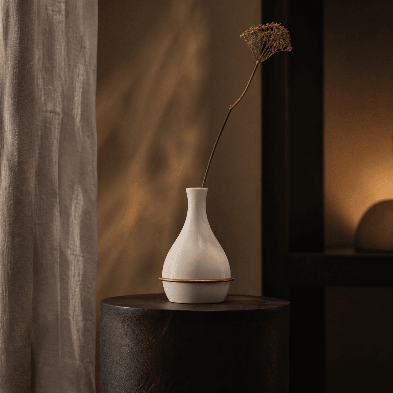 A minimal porcelain bud vase with a muted brass ring detail for a single stem or dried foliage.